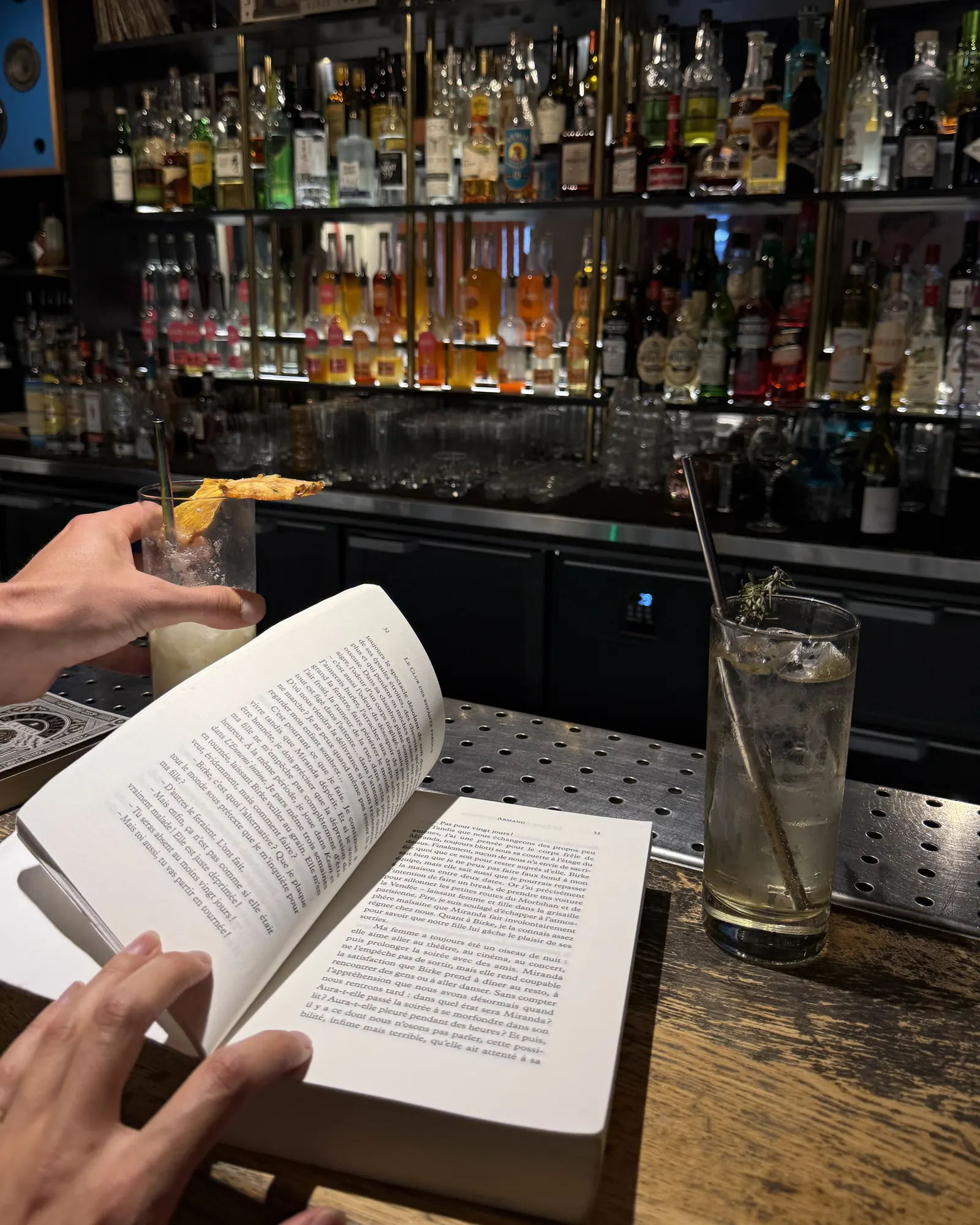 Un livre de poche ouvert sur le comptoir d'un bar, un verre posé à côté