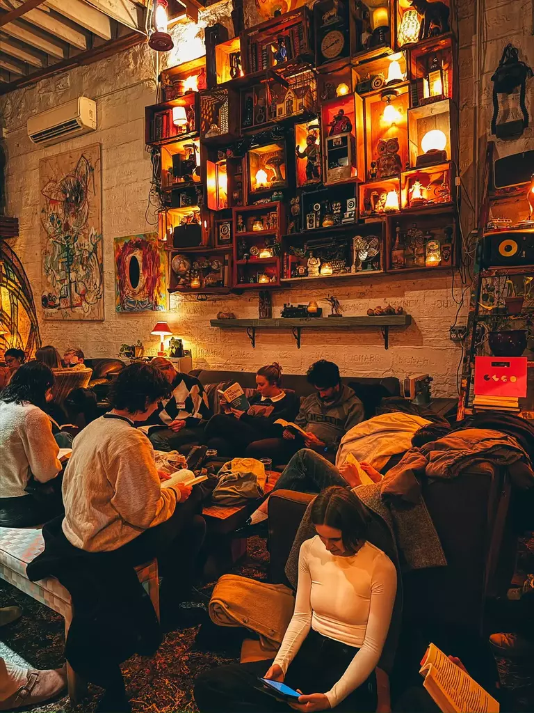 Un salon de bar aux lumières chaudes où plusieurs personnes lisent en silence